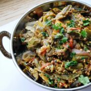 A metal bowl filled with Punjabi bhindi masala, a delightful stir-fry of okra mixed with tomatoes and onions, garnished with cilantro.
