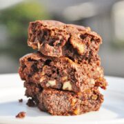 A stack of three chocolate brownies with chunks of nuts graces a white plate, reminiscent of David Lebovitzs Absolute Best Brownies.