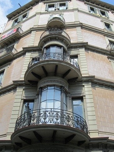 A multi-story building facade featuring ornate wrought iron balconies and large windows.