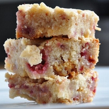 Three stacked raspberry blondies with a crumbly texture on a white surface.