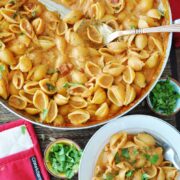 Tikka Masala Pasta in a large pan with a serving spoon and below is a bowl of pasta with cilantro on the side.