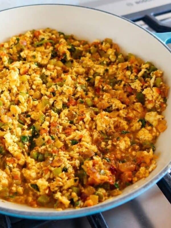 Scrambled paneer with green pepper cooking in a blue skillet on a stovetop, resembling an easy one-pot paneer bhurji.