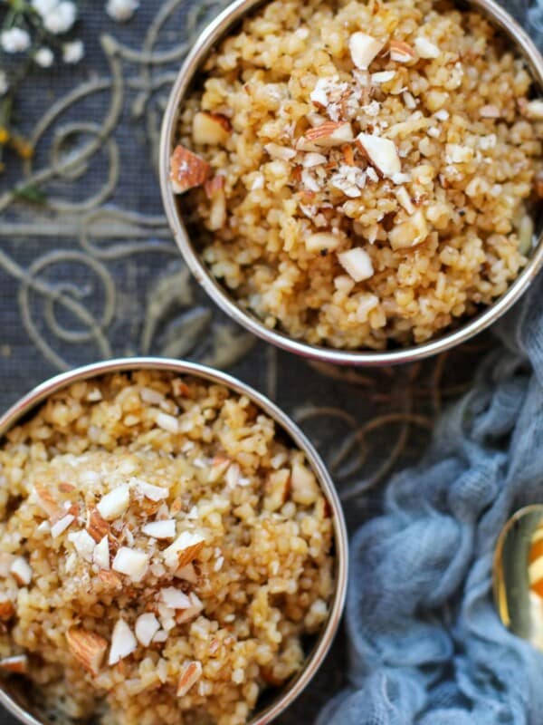 Two bowls of cooked bulgur topped with chopped almonds, placed on a decorative fabric surface.