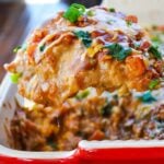 A large piece of Vegetarian Mexican Lasagna covered in cheese and topped with cilantro and scallions.