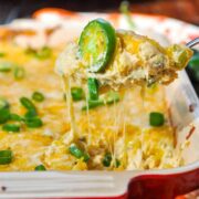 Cheesy pull of Jalapeno Popper Corn Dip being scooped up with a tortilla chip.