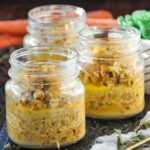 Carrot cake overnight oats divided in 3 mason jars with a couple carrots in the background.