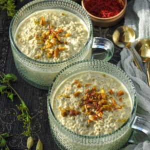 Pistachio Overnight Oats in a fancy glass mug topped with chopped pistachios and a few saffron threads.