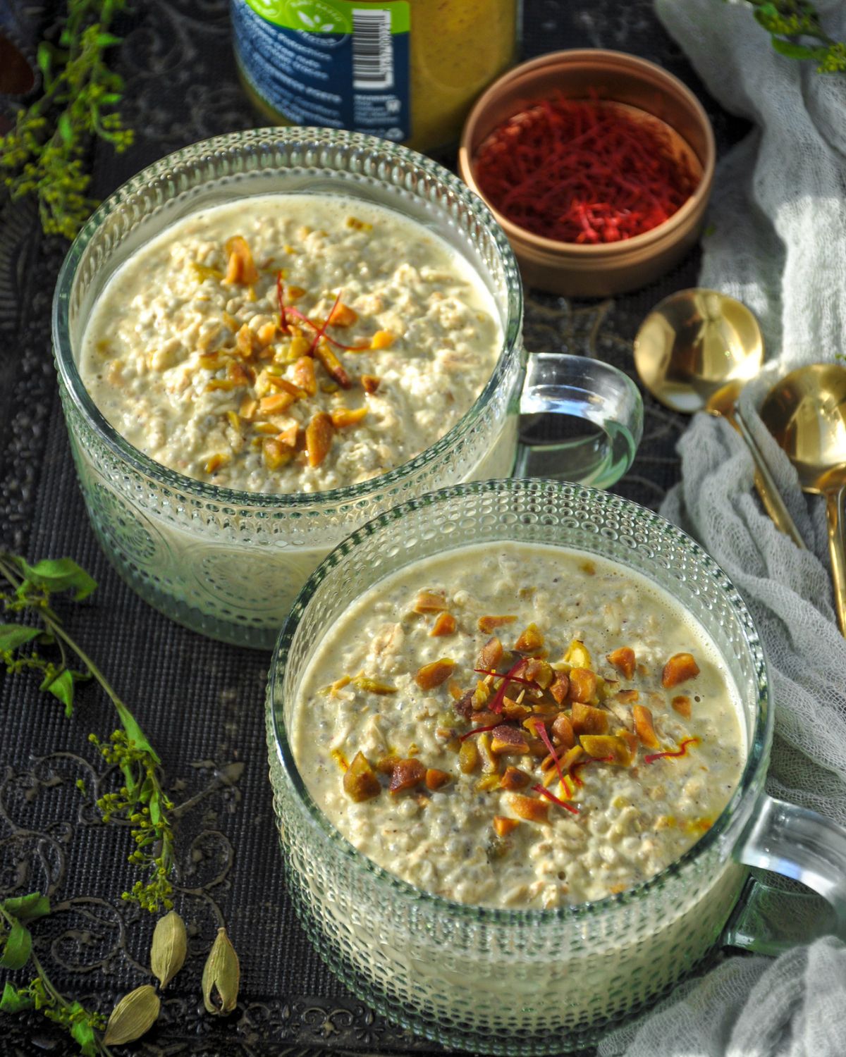 Pistachio Overnight Oats in a fancy glass mug topped with chopped pistachios and a few saffron threads.