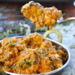 Tofu Tikka Masala in a serving bowl with a large spoon scooping up some of the dish.