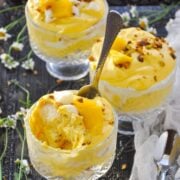 3 small trifle bowls filled with Mango Rasmalai Tiramisu with chamomile flowers in the background.