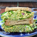 Chickpea Avocado Salad Sandwich layered between whole wheat bread on a blue plate.