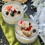Creamy High Protein Overnight Oats without protein powder in 2 fancy cups topped with strawberries, blueberries, and sliced almonds.