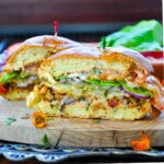 Ultimate Veggie Burger sliced in half consisting of veggies, veggie patty, and a special sauce on a brioche bun.