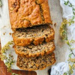 Vegan Banana Bread sliced with a tiny flowers surrounding it.