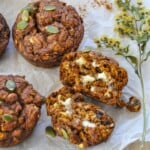 Pumpkin Oat Muffins split in half topped with a little butter that's melting with a couple more pumpkin muffins around.