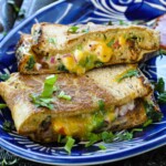 Bread Omelette with veggies and cheese oozing out with a side of tomatoes, onions, and cilantro.