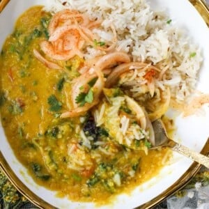 Masoor Dal mixed with jeera rice and laccha onions in a white bowl with gold trim.