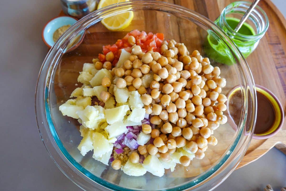 A clear bowl topped with potatoes and chickpeas for Quinoa Bhel Salad.