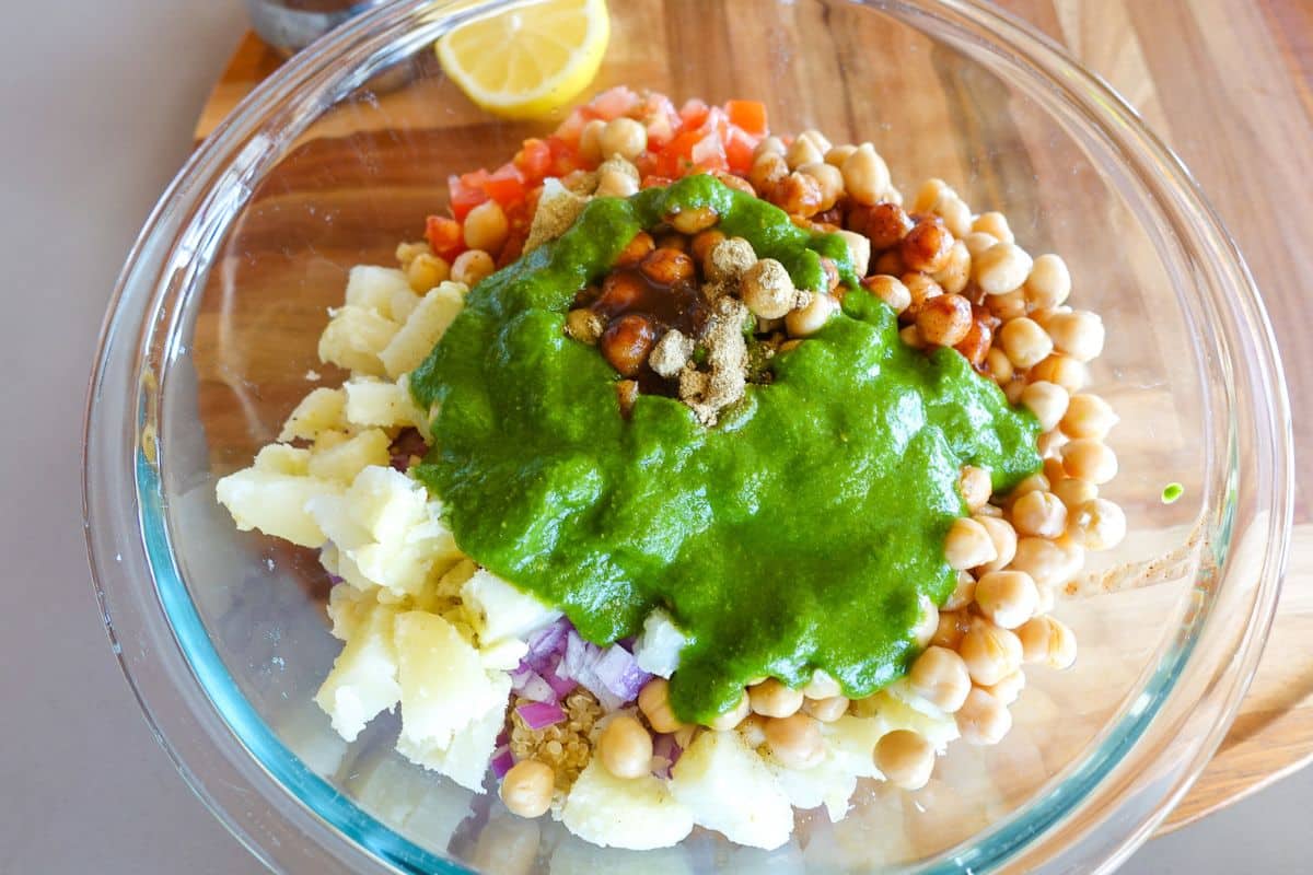 A clear bowl topped with green chutney and chat masala for Quinoa Bhel Salad.