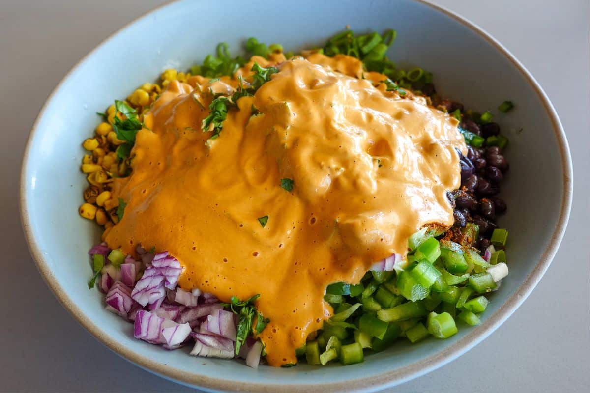 A bowl filled with veggies, topped with a generous serving of creamy chipotle aioli.