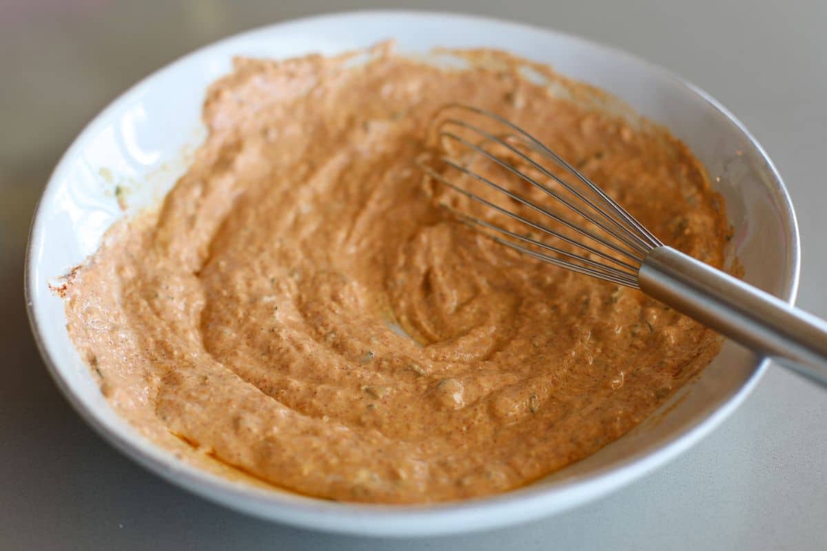 A bowl filled with Paneer Tikka marinade with a whisk.
