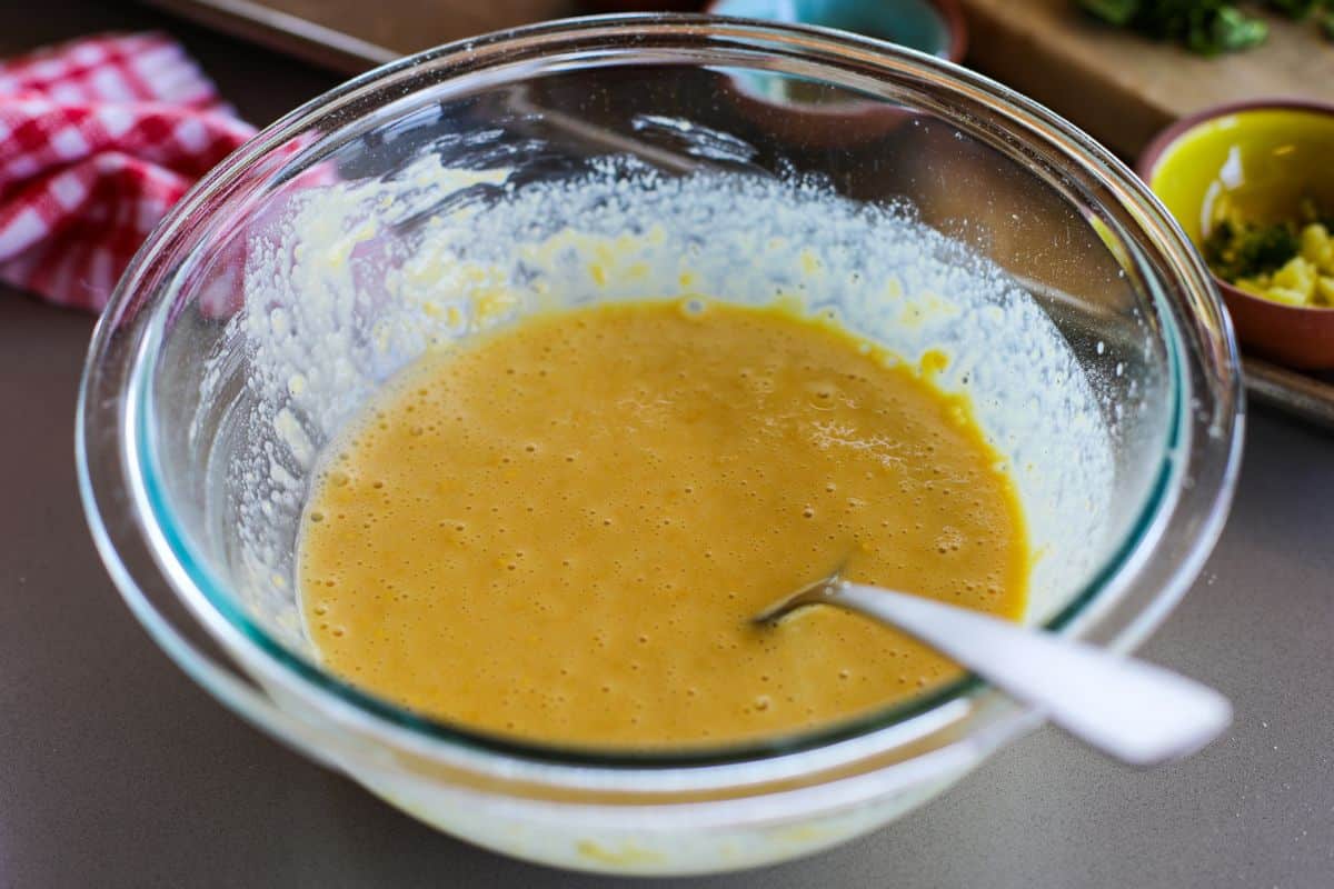 A glass bowl with besan and water mixed together to make spinach besan chilla.