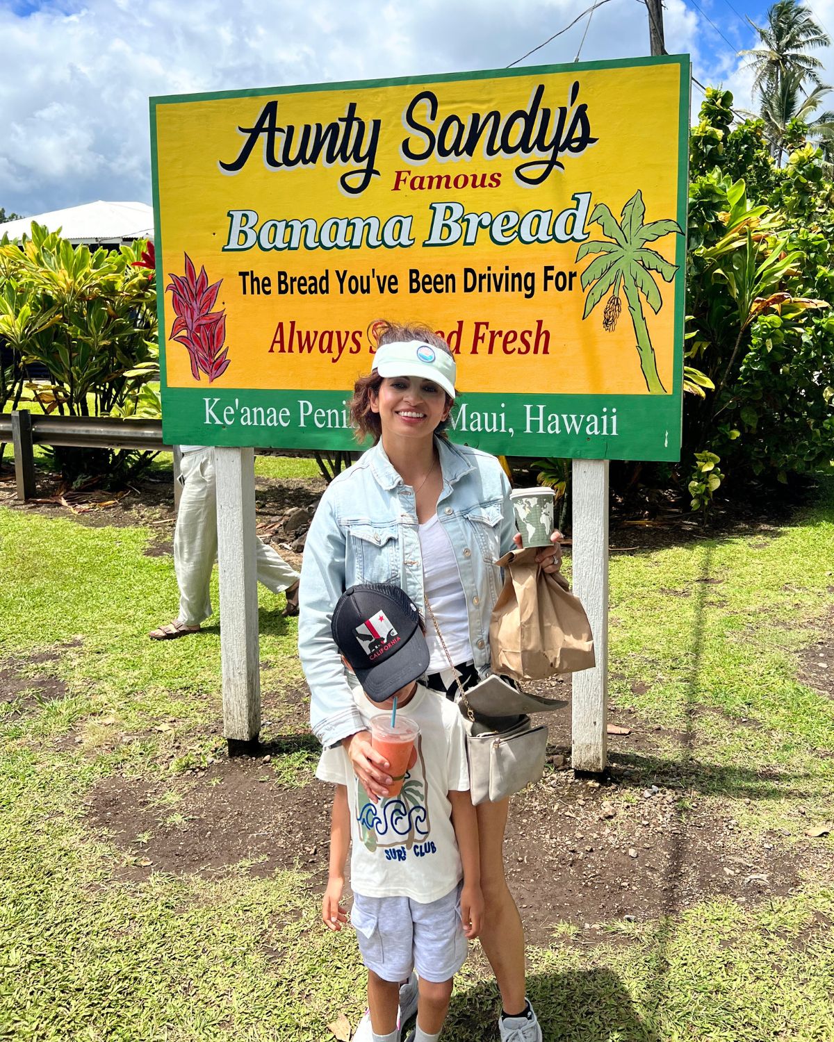 Nisha and son posing in front of Aunty Sandy's Banana Bread in Maui.