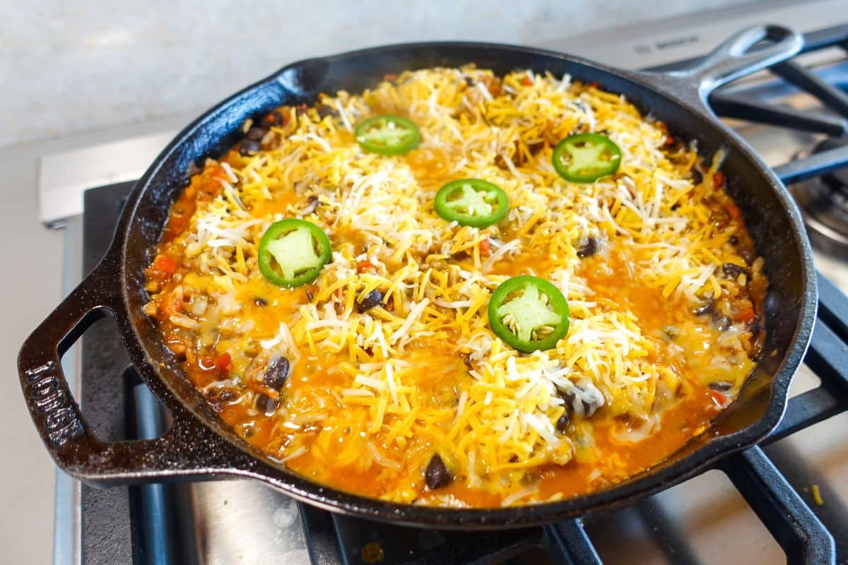 A cast iron skillet topped with cheese and sliced jalapenos.