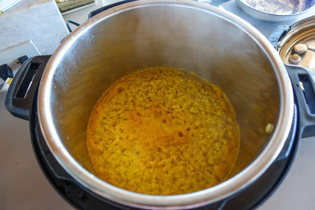 An Instant Pot containing cooked yellow lentils in a liquid.