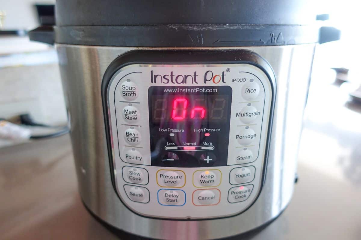 A close-up of an Instant Pot control panel, with the display showing “On” and various function buttons visible.