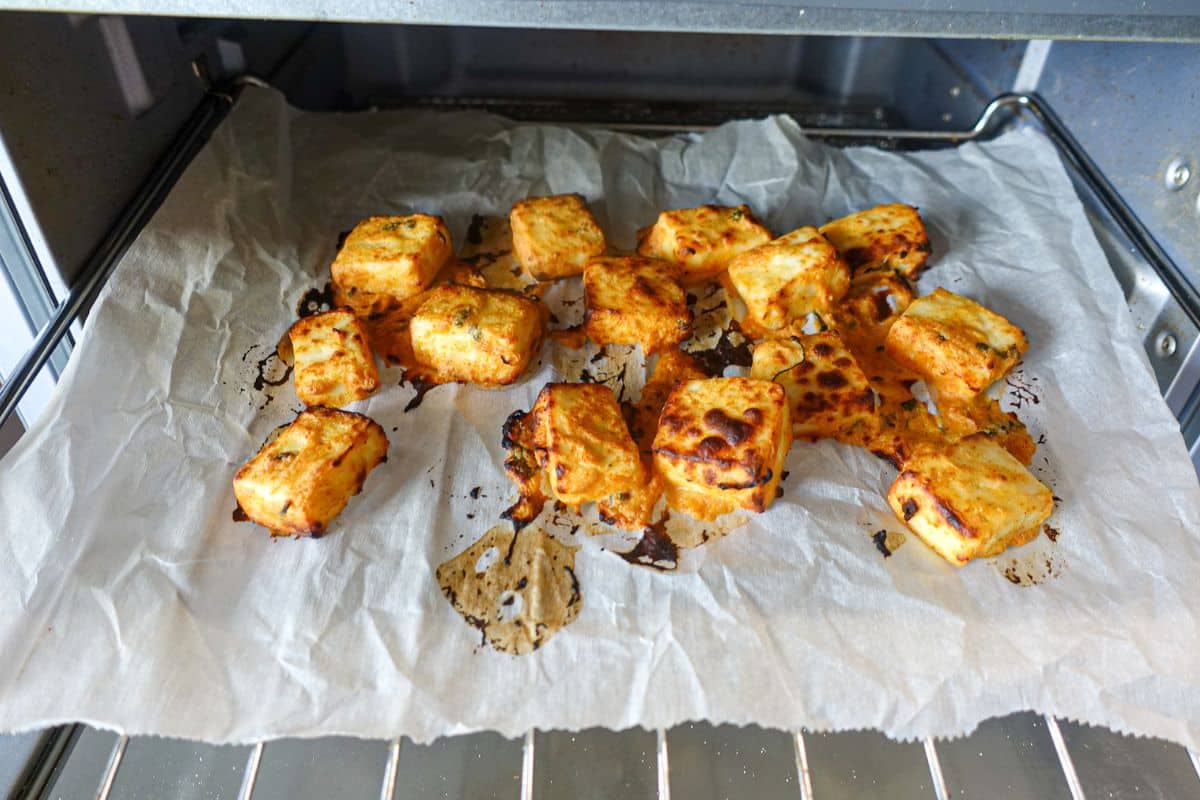 For paneer tikka sliders, air fry paneer and place over parchment paper.