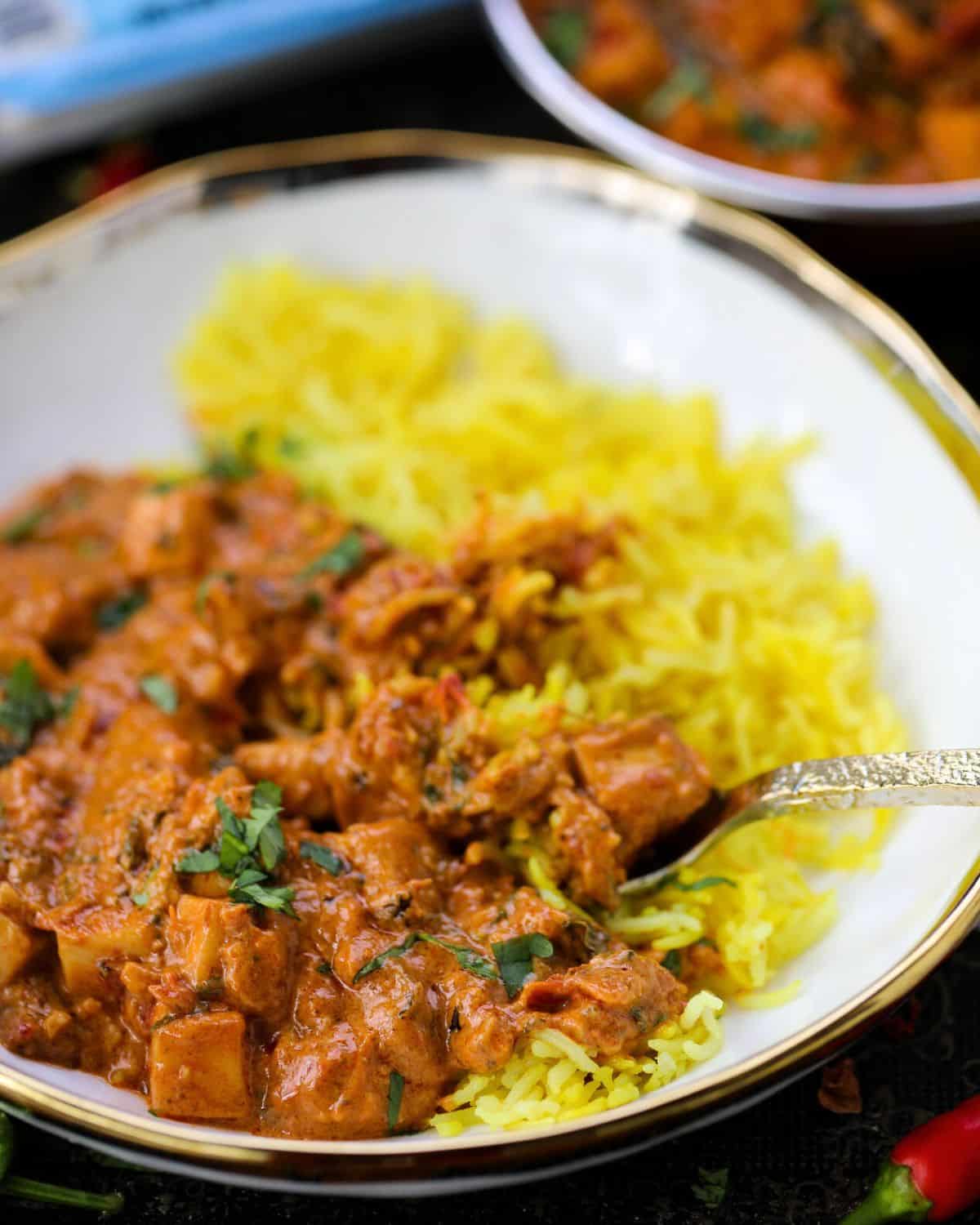Marry me paneer and turmeric rice sit in a white bowl with gold trim around.