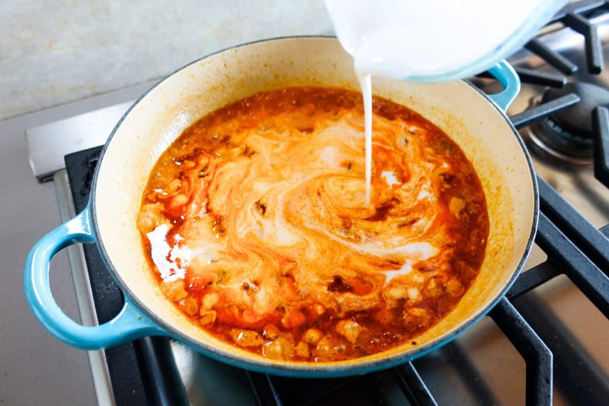 Add coconut milk and milk to an enambled braiser.