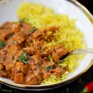 Marry me paneer and turmeric rice sit in a white bowl with gold trim around.