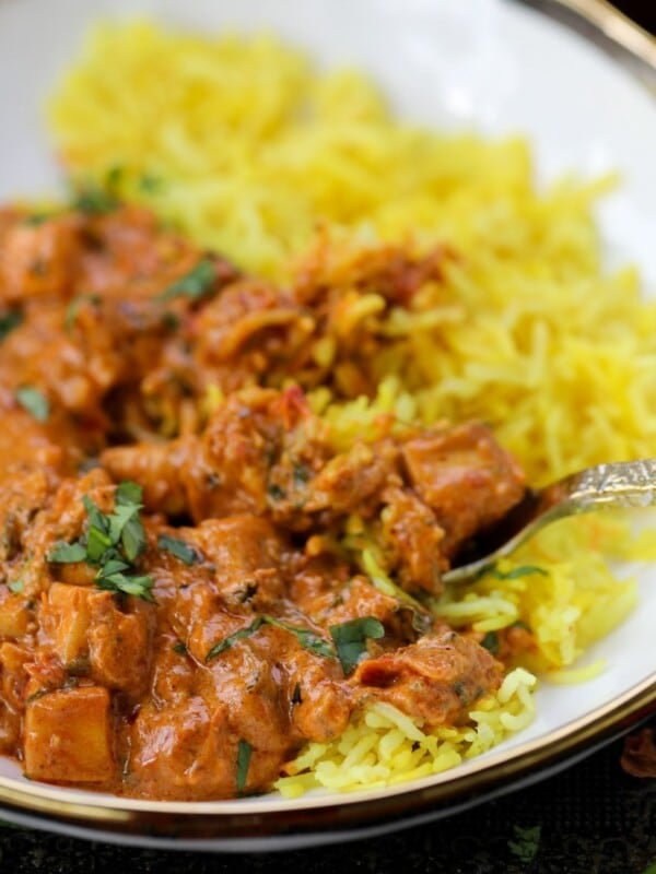 Marry me paneer and turmeric rice sit in a white bowl with gold trim around.