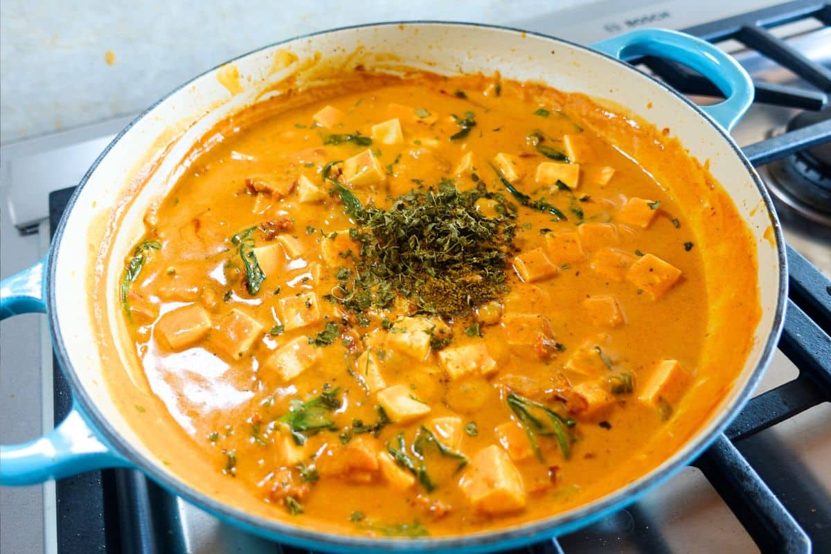 Add garam masala and kasoori methi to a coconut milk sauce with spinach in an enameled braiser to make marry me paneer.