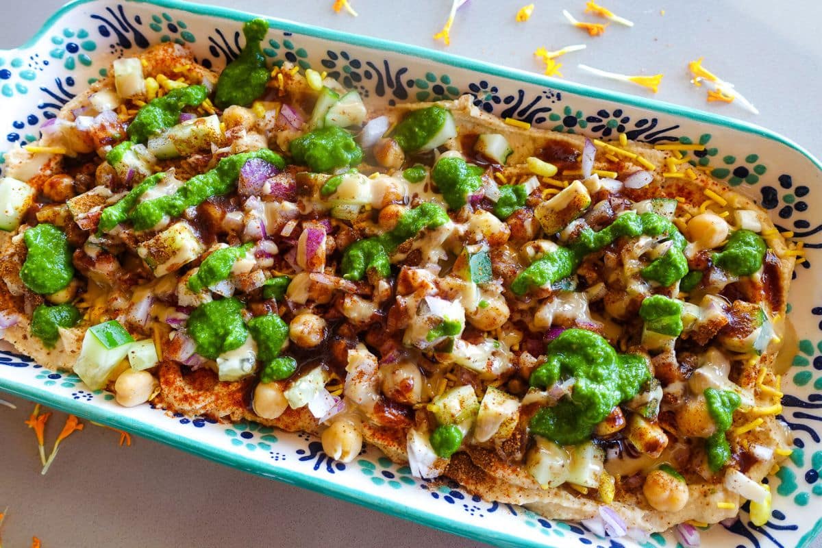 A rectangular platter topped with tahini, green and tamarind chutneys.