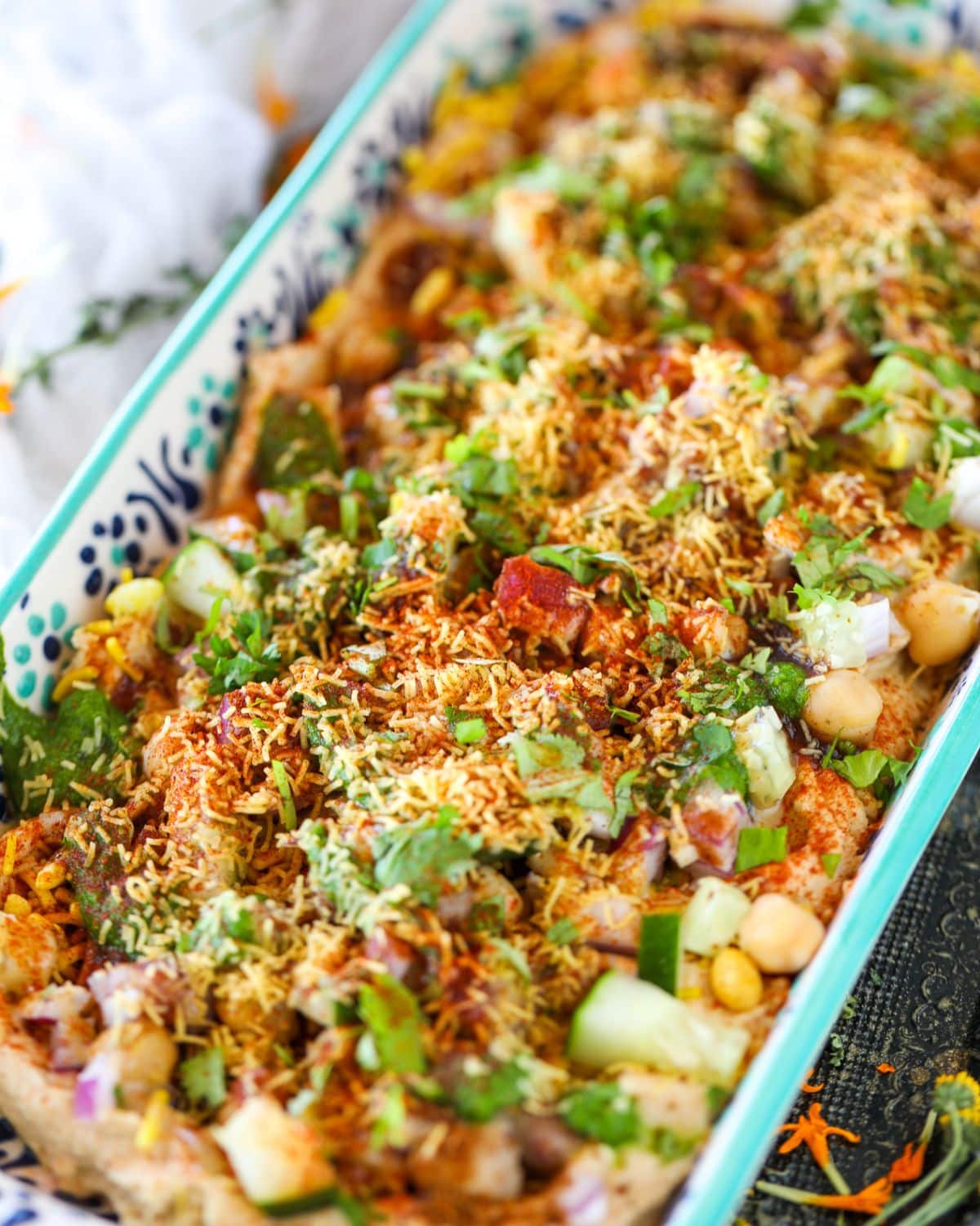 Hummus Chaat Dip is ready sitting on a rectangular dish topped with sev, hummus, and spices.