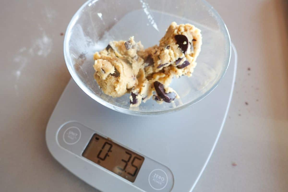 A digital kitchen scale displays 35 ounces with a bowl of chocolate chip cookie dough on top.