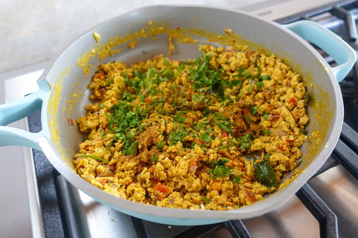 Garam masala and chopped cilantro has been added to cooked egg bhurji in a nonstick pan.