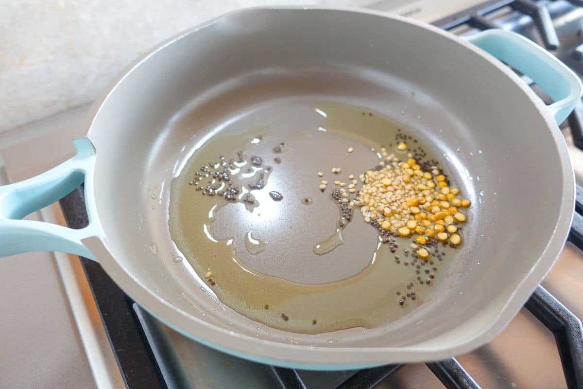 In a pan there is oil, mustard seeds, urad dal, and chana dal to make Egg Bhurji.