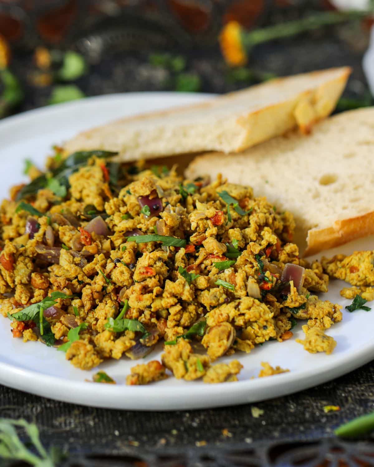 A plate with two slices of toasted bread and a serving of spiced scrambled eggs mixed with herbs.