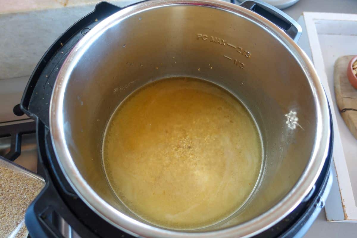 A close-up of an open Instant Pot containing a cracked wheat and water.